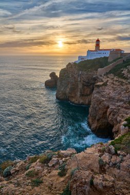Cabo Sao Vicente 'nin kasvetli manzarası, gün batımında güneyde meşhur deniz feneriyle. Sagres, Algarve, Portekiz yakınlarında Avrupa' nın doğu tükürüğü.