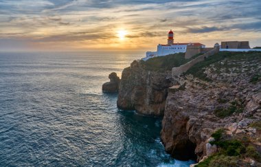 Cabo Sao Vicente 'nin kasvetli manzarası, gün batımında güneyde meşhur deniz feneriyle. Sagres, Algarve, Portekiz yakınlarında Avrupa' nın doğu tükürüğü.