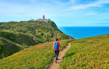 nice woman hiking on the rocky cliffs of Cabo da Roca at the Atlantic coast of Portugal, Europe