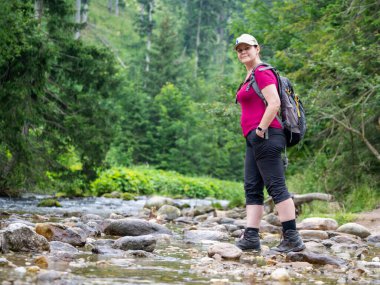 Bir dağ yürüyüşünde, bir kadın dereye uğrar ve yazın etrafına bakar.