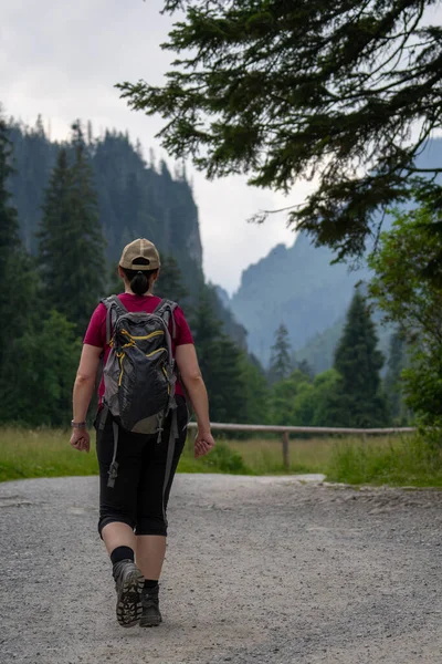 hiking on a gravel path as a woman walks closer to a mountain valley in summer