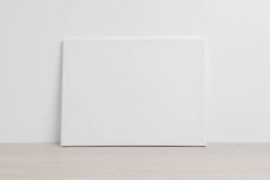 Beyaz bir duvara yaslanmış yatay pozisyonda sanat tuvali. Model sanat sunumu için temiz kumaş