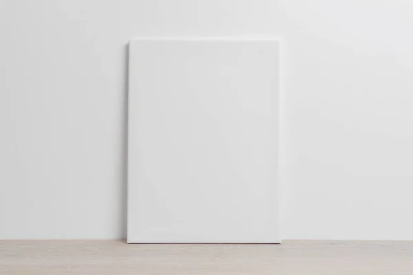 白い壁に寄りかかって床にアートキャンバスのモックアップ — ストック写真