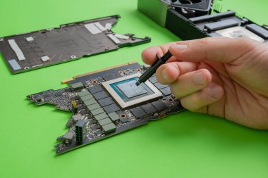 Changing the thermal paste on the graphics processor. Disassembled graphics card on the table. Old graphics card service