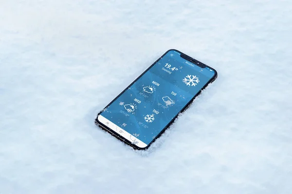 Phone in the snow with a weather app. Temperature in fahrenheit with forecast for several days