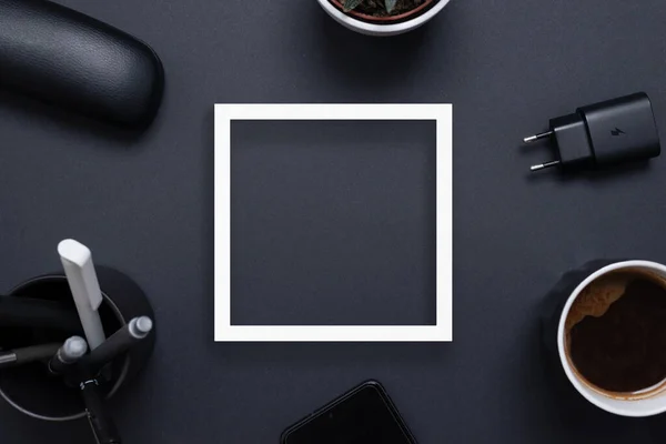 Weißer Quadratischer Papierrahmen Auf Schwarzem Schreibtisch Umgeben Von Kaffeebecher Ladegerät — Stockfoto