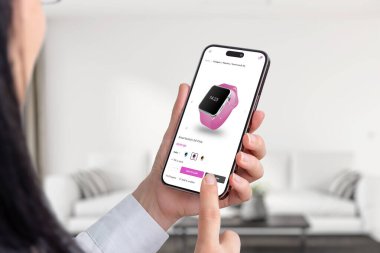 İnternetten akıllı saatler almak. Renk değiştirme düğmeleri olan modern ekommerce uygulaması. Cep telefonu tutan kadın. Oturma odası arka planda.