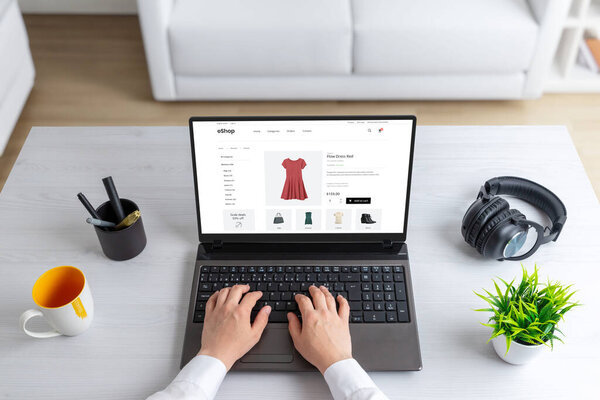 Стильная женщина исследуя одежду в Интернете, покупки, выбирая красивое красное платье, которое идеально дополняет ее вкус и личность