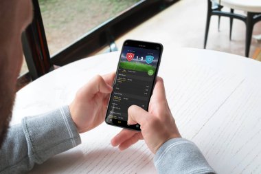 Adam bir cep telefonu uygulaması üzerinden futbol maçında bahis oynuyor. Online spor bahisleri konsepti. Mobil platformlar için modern bir uygulama