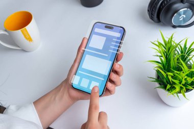 Kavramsal kullanıcı arayüzü olan akıllı telefon tutan bir kadın. Arayüz, canlı renkleri ve sezgisel navigasyon elemanlarına sahip temiz bir tasarım sergiliyor.