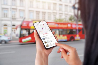 Şehir turu uygulaması akıllı telefondan kadınların eline geçti. Arka planda şehir turist otobüsü