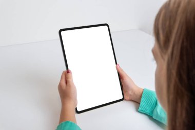 Çalışma masasında bir kızın tuttuğu dikey tablet. İzole edilmiş ekranlı oyunlar ya da uygulamalar için mükemmel. Modern teknoloji genç bir kullanıcının ellerinde