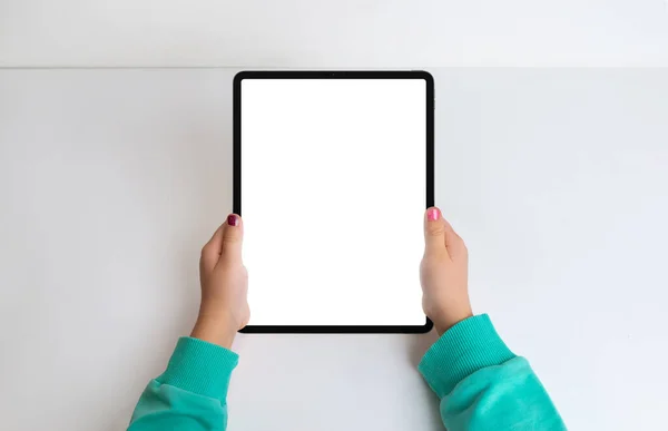 Girl\'s hands with tablet in a top view flat lay, featuring an isolated screen for mockup. Create a modern aesthetic for digital content and app presentations