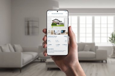 Emlak uygulaması insan eliyle telefon ekranında. Zahmetsiz ev arama deneyimi için emlak listeleri
