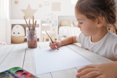 Odasında beyaz kağıda suluboya boyayla resim yapan genç bir kız. Çocukların yaratıcılığı ya da sanatsal kavramlar için ideal