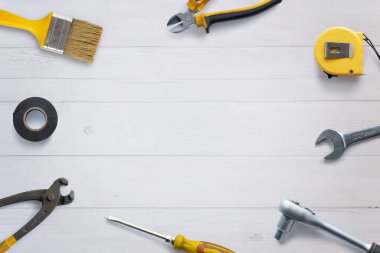 Ortasında kopya alanı olan beyaz ahşap bir masanın üzerine düzgünce yerleştirilmiş çeşitli araçların üst görünümü. DIY konsept tanıtımı için düz kompozisyon ideal