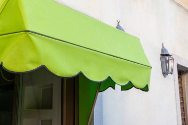 Dükkan penceresinin önündeki yeşil tente. Yazdırma logosu veya metin için boşluk. Mağaza reklamı ve markalaşma fırsatları için mükemmel.