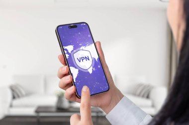 Elinde VPN bağlantısı olan akıllı telefon tutan bir kadın, ekranda bir dünya haritası gösteriyor. Küresel çevrimiçi güvenlik ve mahremiyet vurgusu