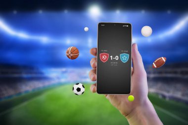 Cep telefonunun elinde çeşitli spor toplarının uçuştuğu bir uygulamadan eşleşen sonuçlar var. İnternette canlı skorlar ve spor bahisleri 
