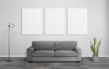 Oturma odasında üç tablo, kanepe, bitki ve lamba. Model sanat sunumu ve ev dekorasyonu için beyaz temiz tuval yüzeyleri