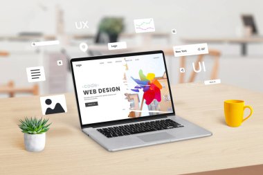 Web tasarım stüdyosunun web sayfasını gösteren bir çalışma alanındaki dizüstü bilgisayarda, dinamik web sitesi oluşturma ve tasarım entegrasyonu kavramını gösteren grafik web modülleri ve elementler havada uçuşuyor.