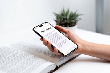 Elde telefon OCR tarama kavramlı kitap çeviri uygulamasını gösteriyor. Dil öğrenme, çeviri teknolojisi, okuma ve dijital eğitim konuları için ideal