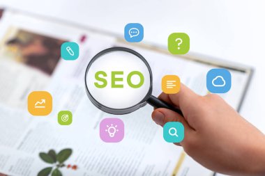 SEO metin ile el ele tutuşan büyüteç inceleme kitabı, fikirler için kavramsal simgeler, bulut, arama, hedef ve metin etrafında yüzüyor