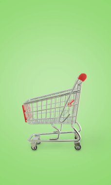 Yeşil arka planda bir süpermarketten alışveriş arabası, perakende, tüketim ve modern alışveriş deneyimlerini sembolize ediyor.