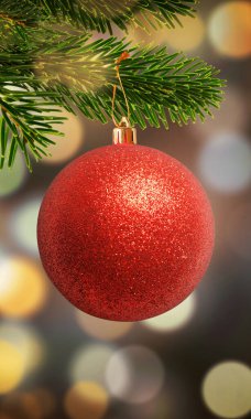 Vertical close-up of a red Christmas ornament on a tree with bokeh lights in the background, featuring space for promotional text or a logo clipart