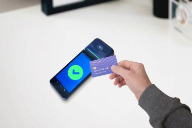 Bir POS terminali üzerinden elinde bir kredi kartı tutarken başarılı bir ödeme olduğunu gösteren yeşil renkli bir ikon. Güvenli işlemlerin bir temsili