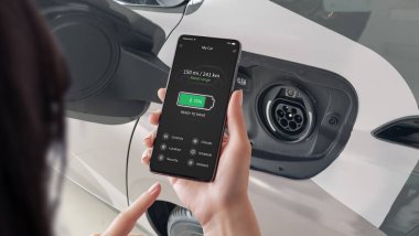 Akıllı hareketlilik kavramı bir EV kullanıcısının şarj cihazının bağlantısını kesmesi ve pil durumunu doğrulaması ve akıllı telefon uygulamasında tahmini sürüş aralığı