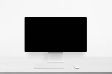 Bilgisayar monitörlü minimalist beyaz masa, boş ekran, klavye ve fare, web arayüzlerini, markalaşmayı veya dijital tasarım çalışmalarını göstermek için ideal