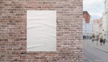 Kaldırımın kenarındaki tuğla cephesinde boş posterli şehir caddesi manzarası. İzleri, reklamları veya görsel içeriği desteklemek için mükemmel bir model..