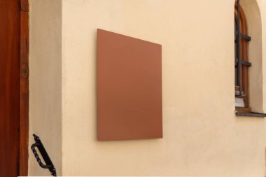 Bej renkli duvarda minimalist kahverengi kare işareti, markalaşma, isim tasarımı veya küçük işletme kimliği için ideal