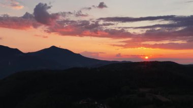 Kırmızı ve morun zengin renkleri, ormanın derinliklerine batan güneş ışığının son anları gibi gökyüzüne hakim oluyor.