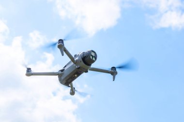 Mavi gökyüzünün altında ileri bakan kameralı uçan İHA 'nın yakın görüntüsü