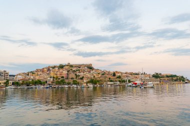 Kavala 'nın eski şehir ve kalesinin geniş açılı görüntüsü körfezin üzerinde, geleneksel evler ve sakin mavi sularla yükseliyor.