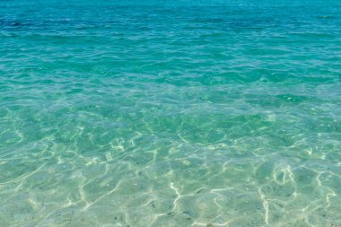 Güneş ışığı yansımalı sığ turkuaz deniz kumlu zeminde büyüleyici desenler yaratıyor. Yaz ve tropikal temalar için mükemmel.