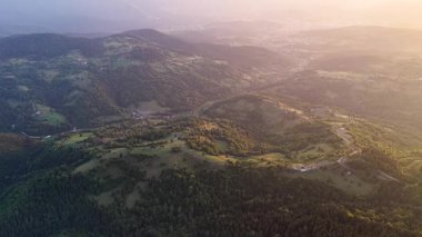 Romanya 'da tepelere ve dağınık evlere altın ışık düşüyor, ağaçların ve arazilerin katmanlarını aydınlatıyor