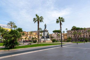 Roma, İtalya 'daki Piazza Cavour Meydanı' ndaki heykel, palmiye ağaçları ve renkli tarihi binalarla çevrili.