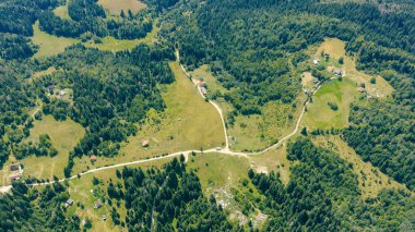 Yazın kırsal yolları, evleri ve ormanları olan dağ manzarası.