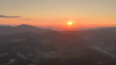 Trebevi Dağı 'nın arkasındaki katmanlı dağ sırtlarıyla gün batımının manzarası.