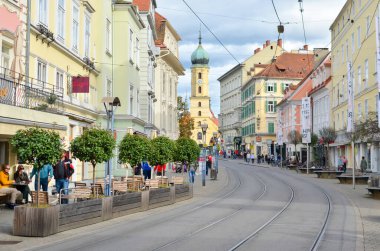 Graz Avusturya 8 Ekim 2017: Tramvay raylı sokak manzarası, renkli binalar ve arka planda kilise kulesi