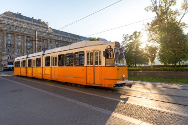 Budapeşte, Macaristan 'da gün batımında şehir merkezinden geçen klasik sarı tramvay.