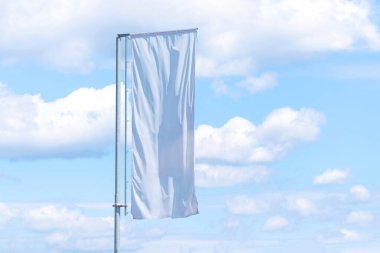 Tek uzun dikey beyaz pankart rüzgarda dalgalanan mavi gökyüzü arkaplanı, açık hava reklam alanı