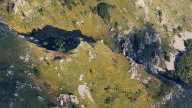 4K insansız hava aracı görüntüleri engebeli dağ uçurumları üzerinde uçuyor, dağlık kayaların ve çayırların dokularını vurguluyor..