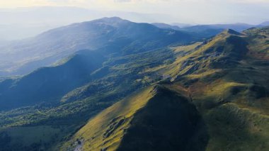 Dağ sırtları ve dağlık vadilerde dramatik güneş ışığı ve gölgeleri vurgulayan 4K videosu.