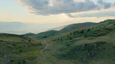 Alp yamaçlarının ve yeşil çayırların dramatik yaz bulutlarıyla süpürülmüş görüntüsü..