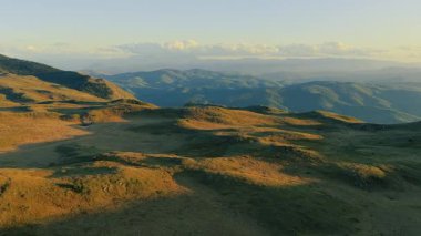 İHA görüntüleri alacakaranlıkta yumuşak altın ışığın altında katmanlı çıkıntıları ve vadileri gösteriyor.