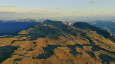 Sıcak yaz günbatımında parlayan alp sırtlarını ve vadileri yakalayan hava 4K görüntüleri.